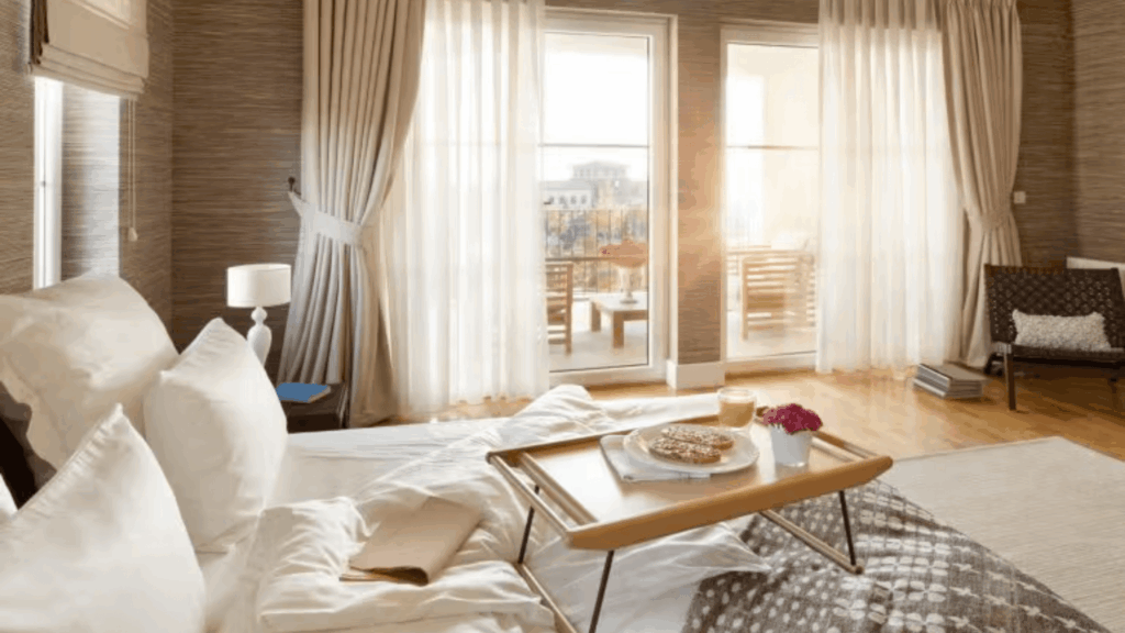 25 Best Curtain Styles for Every Home soft white sheer window curtains beside bed with breakfast tray and bright balcony doors in cozy bedroom curtain styles