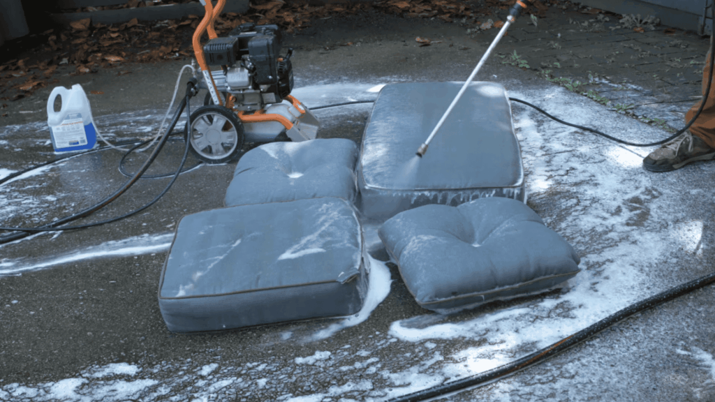 spraying cleaning solution on outdoor cushions evenly using a pressure washer safely
