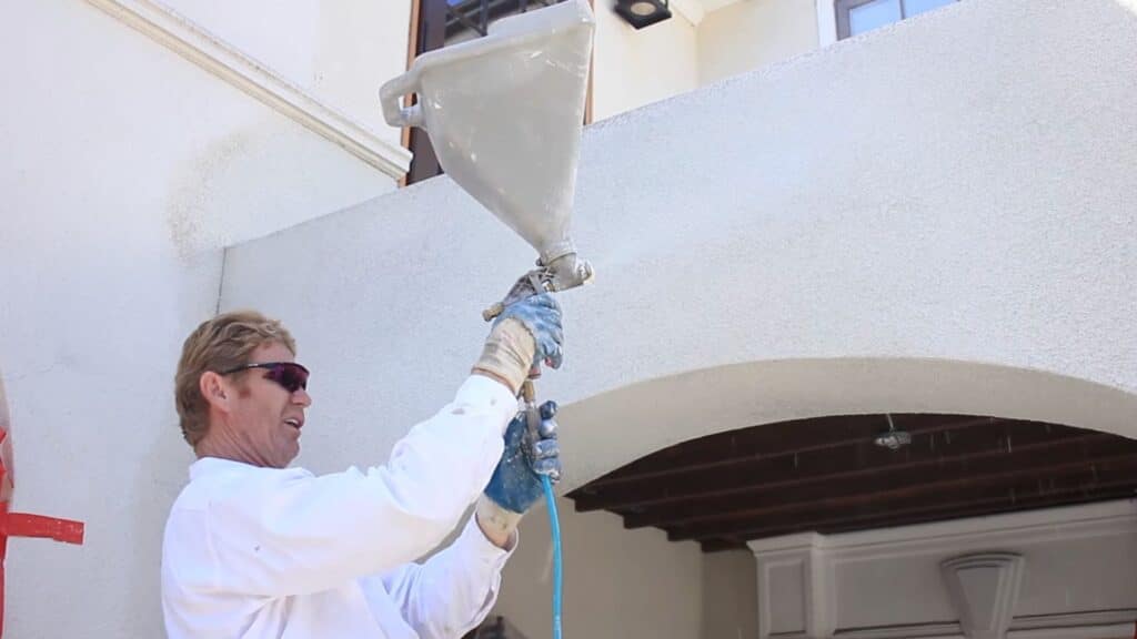 spraying dash finish on stucco wall using hopper gun for rough texture