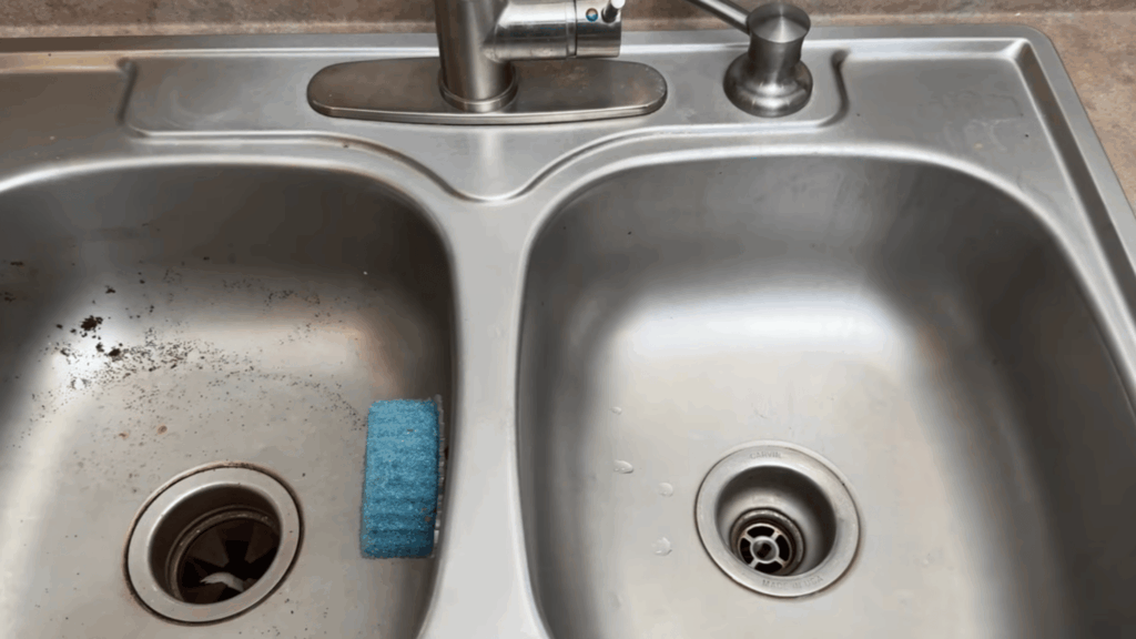 stainless steel kitchen sink showing dirty and clean sides with sponge near drain simple home cleaning