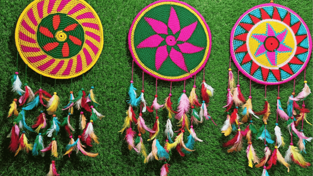three colorful handmade dreamcatchers with crochet patterns and bright feathers hanging on green background for homemade gifts made easy