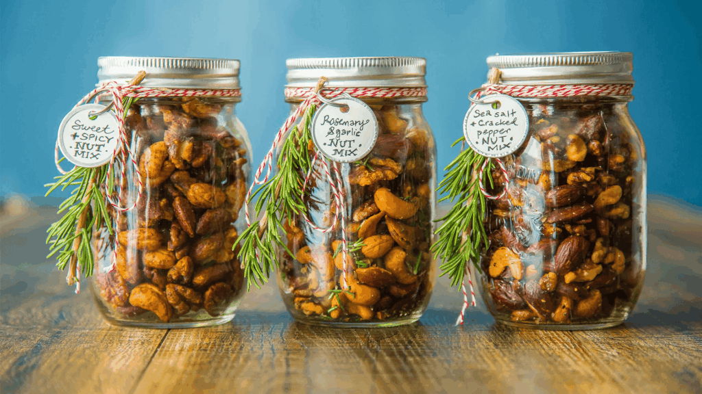 three jars of seasoned mixed nuts with rosemary and labels on wooden table for homemade gifts made easy