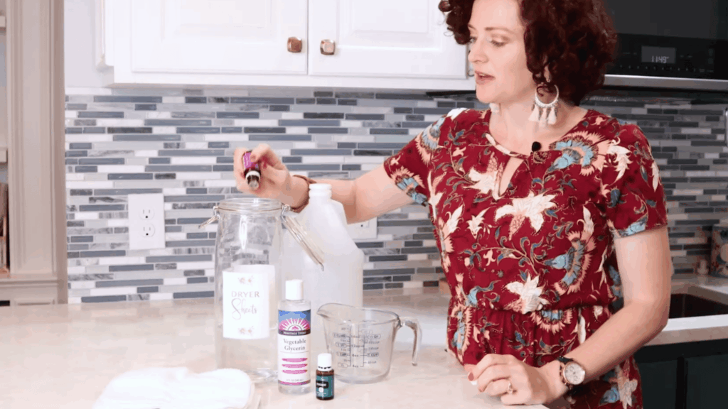 woman adding essential oils into jar to create natural scent for homemade dryer sheets preparation