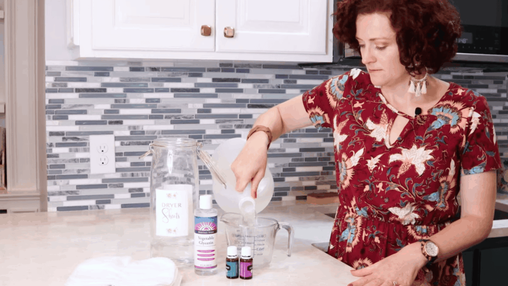 woman pouring water and vinegar into measuring cup for homemade dryer sheets