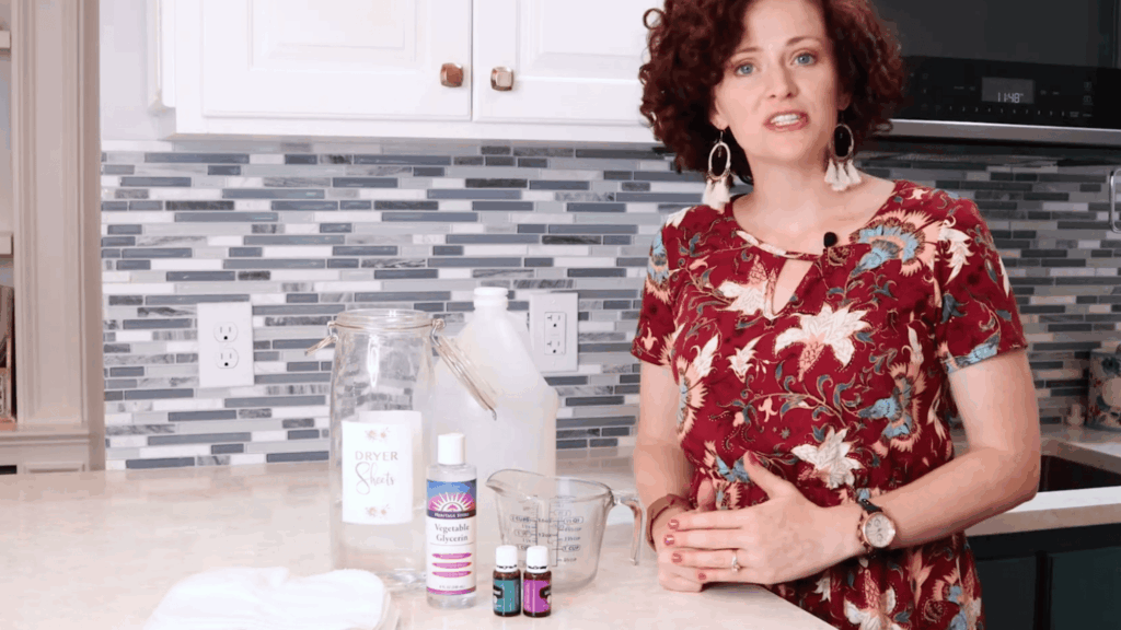 woman showing ingredients like cloth wipes vinegar essential oils and jar for homemade dryer sheets