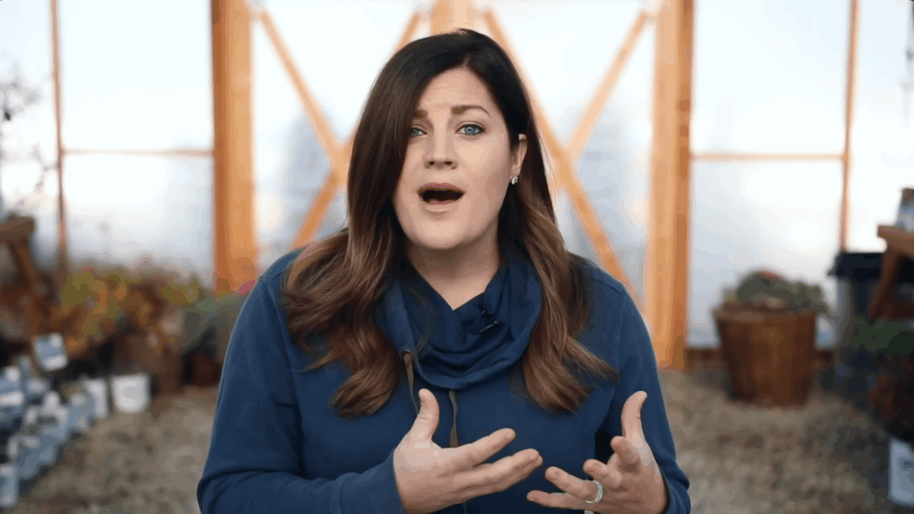 woman speaking indoors with plants behind her explaining gardening tips with hand gestures