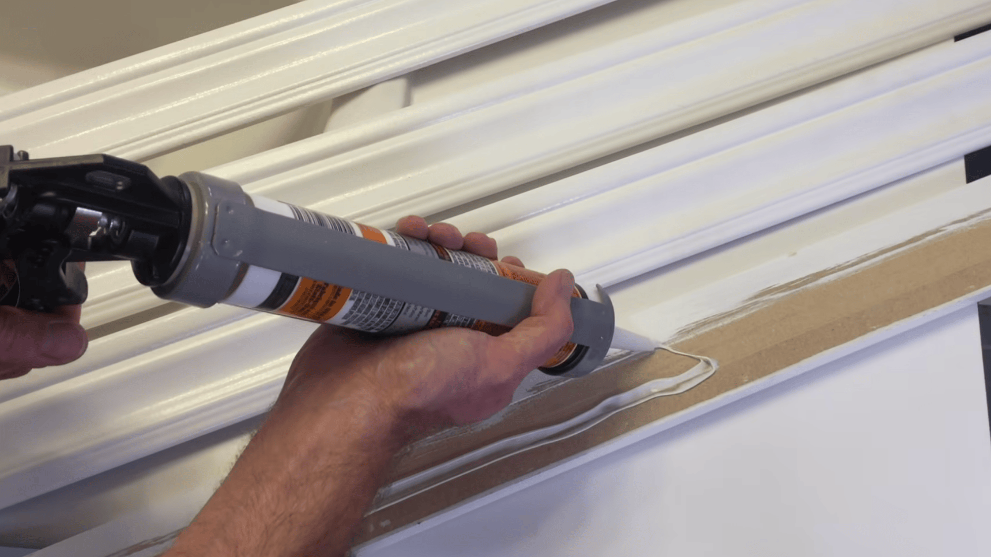 applying glue along trim back using caulk gun to ensure strong hold for mirror frame attachment process