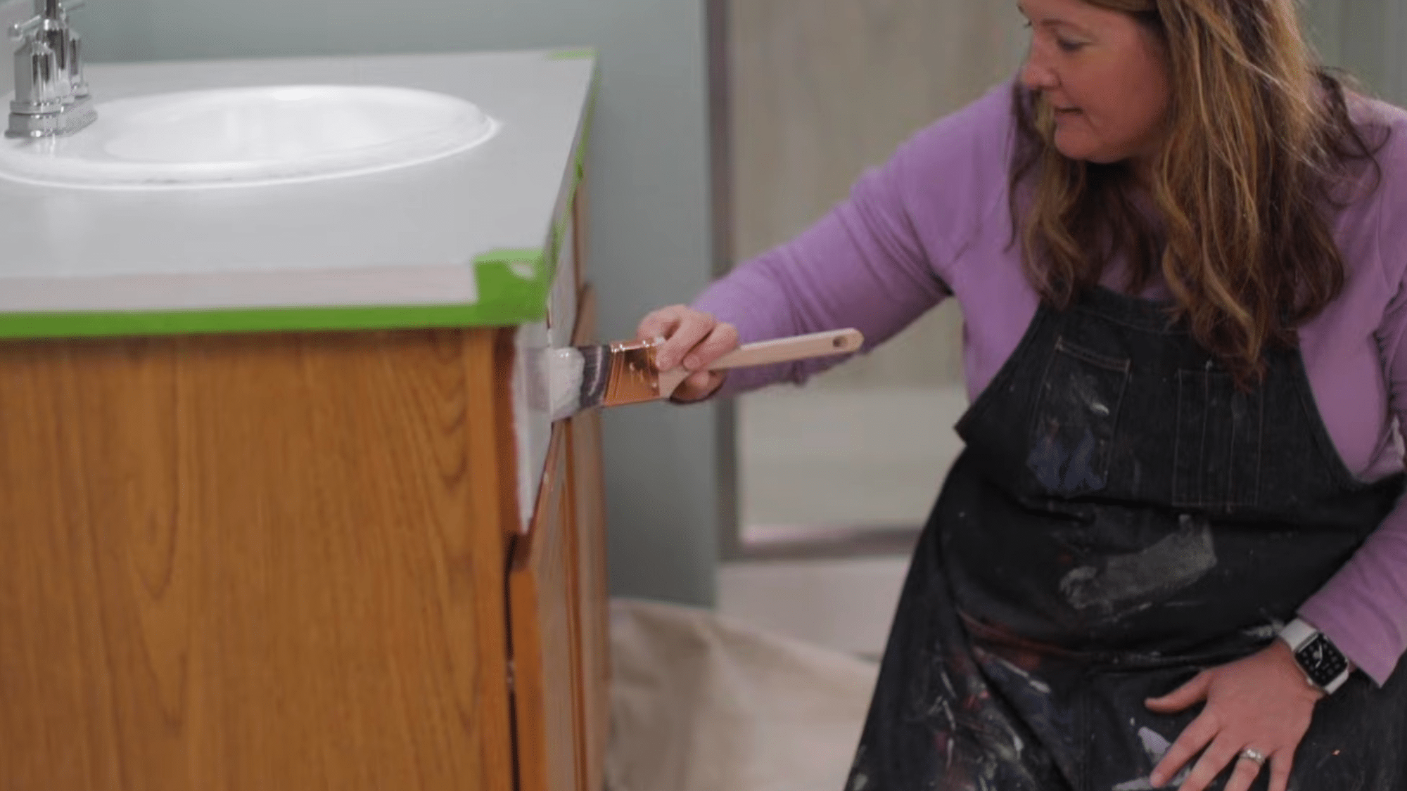 applying primer with a brush while painting bathroom cabinets to create a smooth base for better paint adhesion