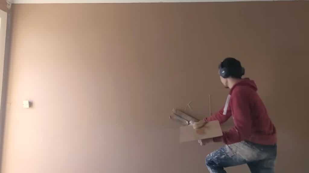 applying second coat of plaster to smooth wall surface with controlled strokes and even finish