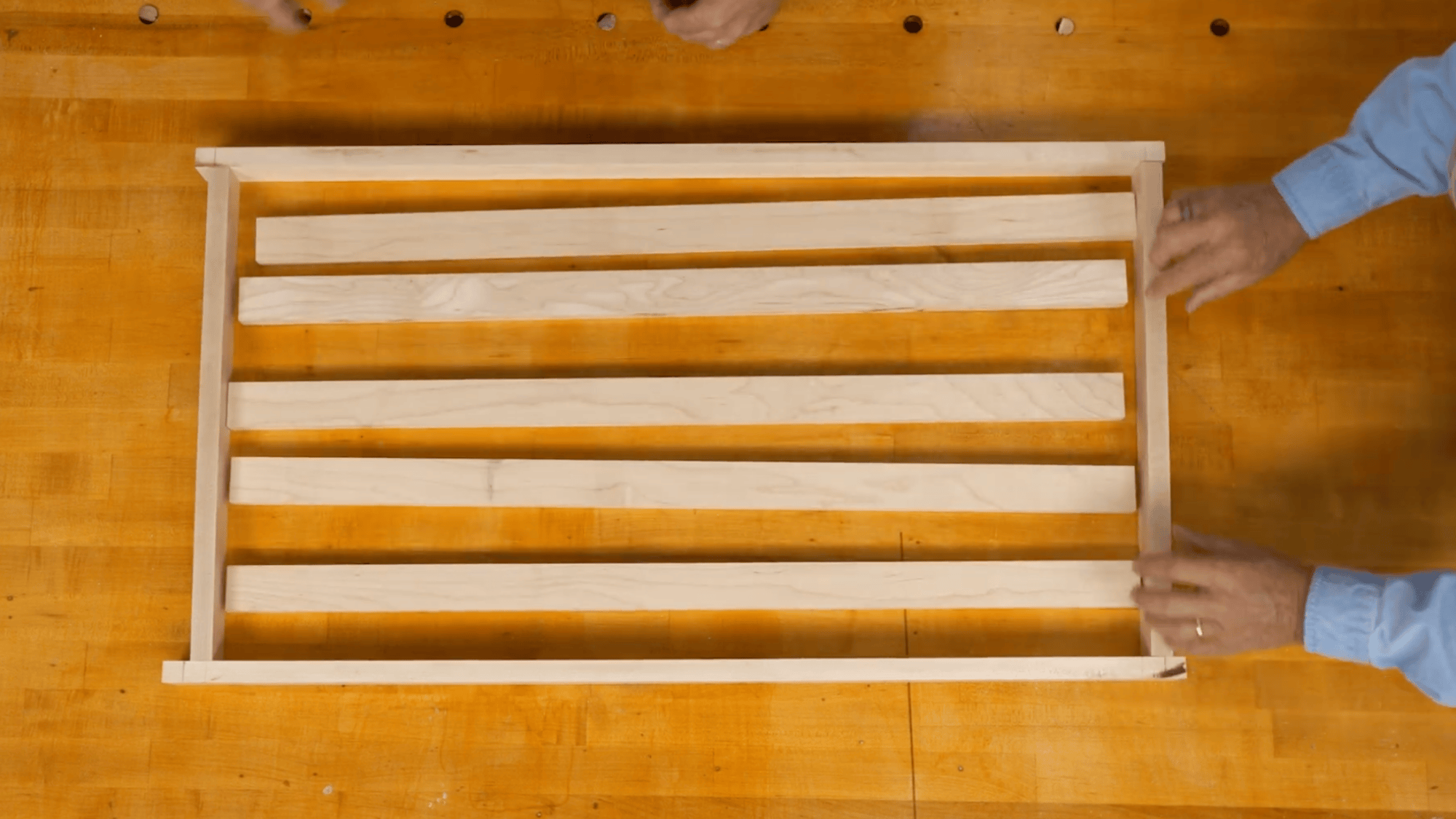 arranging wooden slats to build bottom shelf layout for diy clothes rack with even spacing on frame