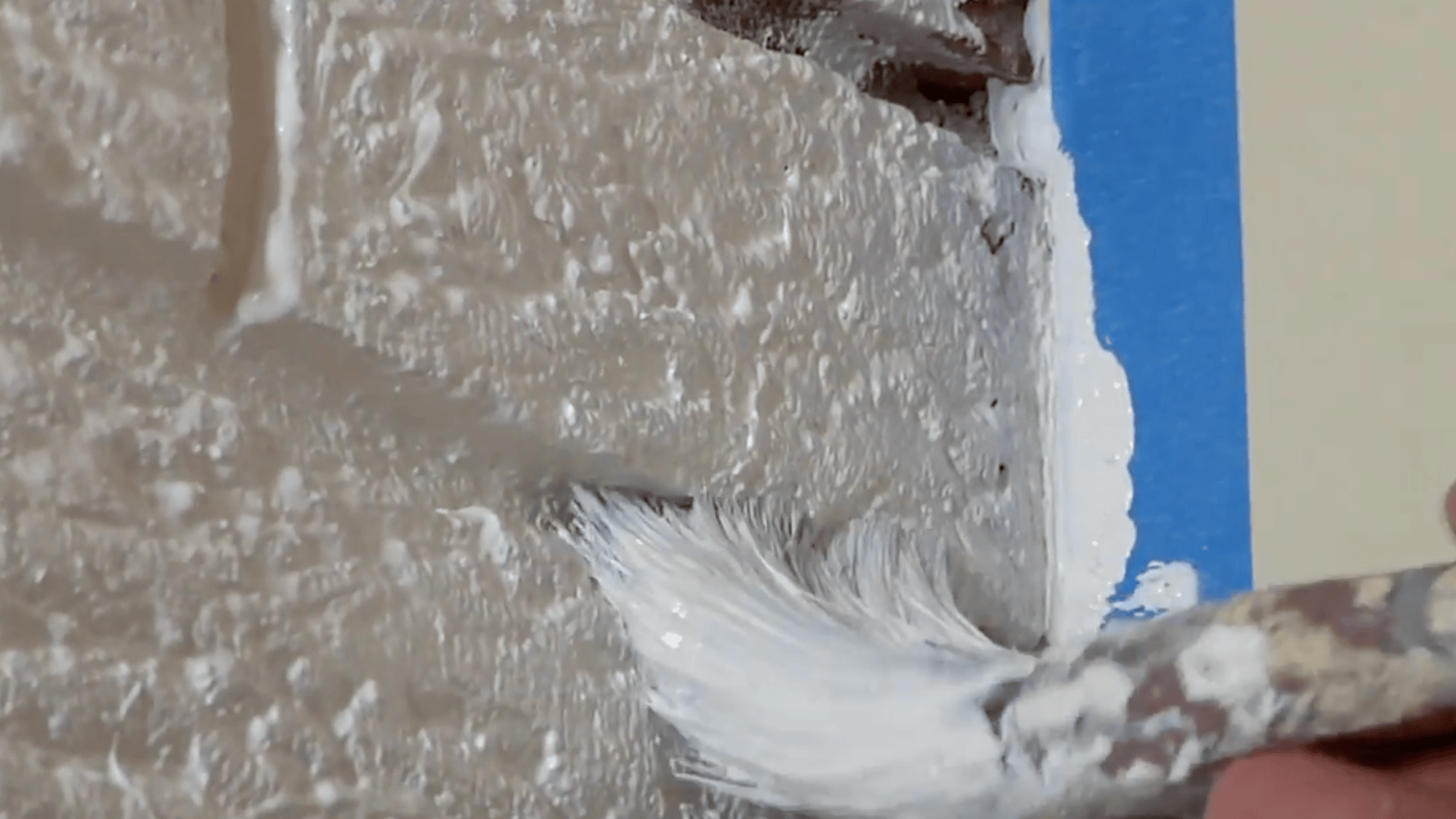 brush applying primer evenly on textured brick surface