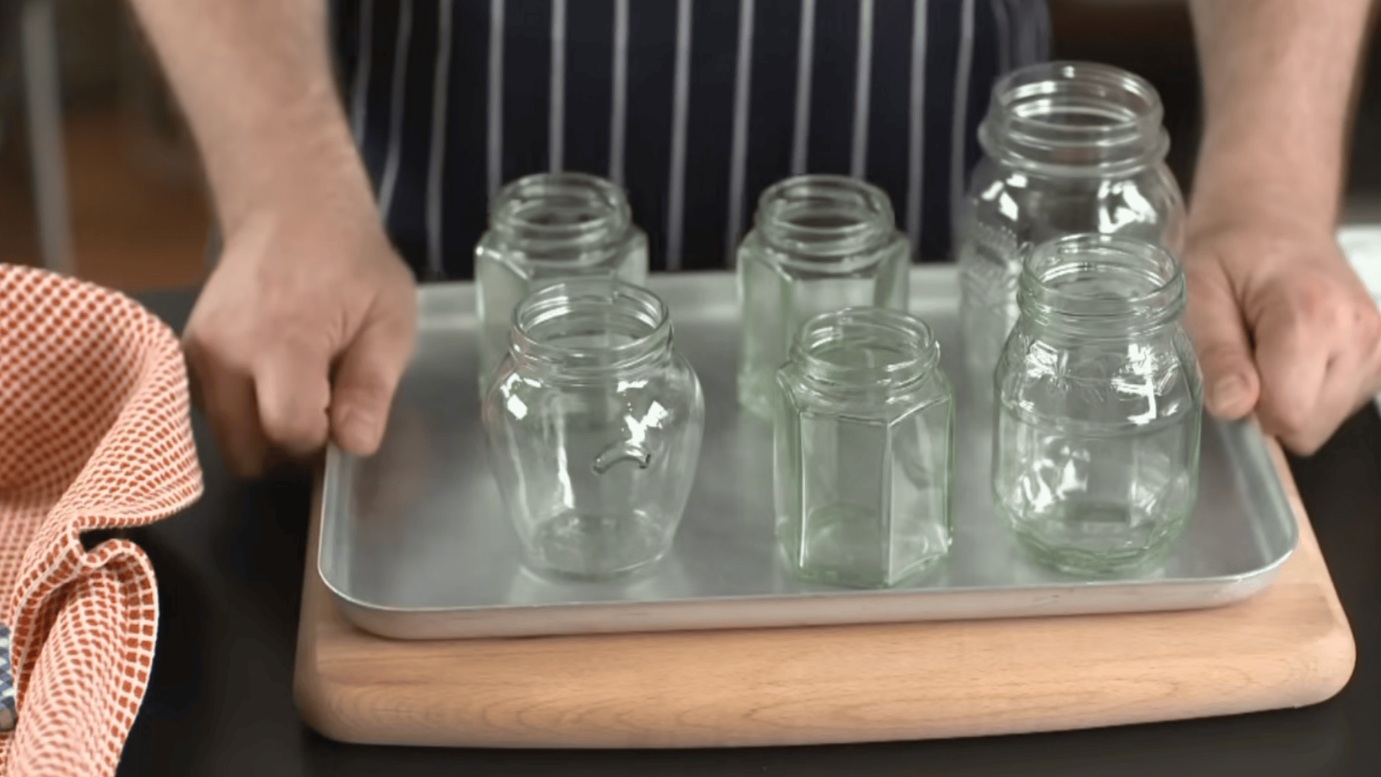 clean glass jars arranged on metal tray with space between each jar ready for oven sterilizing step