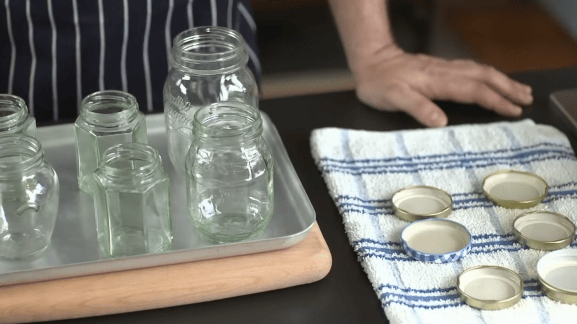 clean hot jars on tray with dry lids placed on cloth ready to fill and seal for safe food storage at home