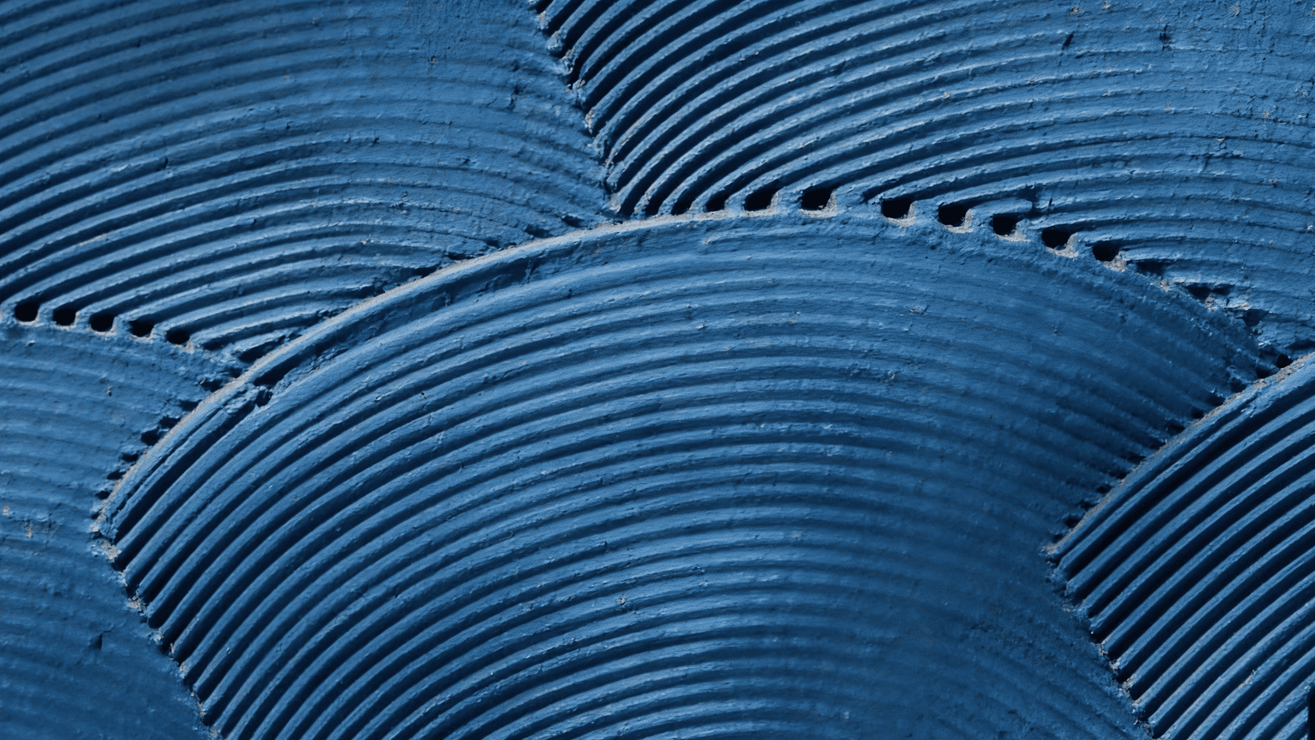 close up of blue textured wall with layered curved ridges forming repeating wave pattern across surface