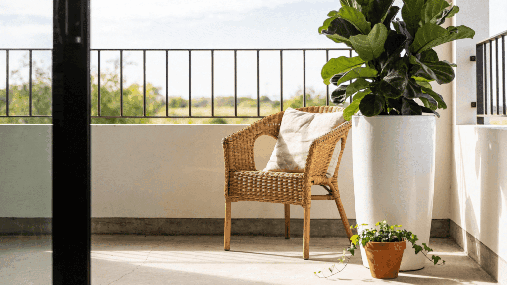 cozy balcony garden ideas with wicker chair cushion and potted plants in sunlight beside railing and open view
