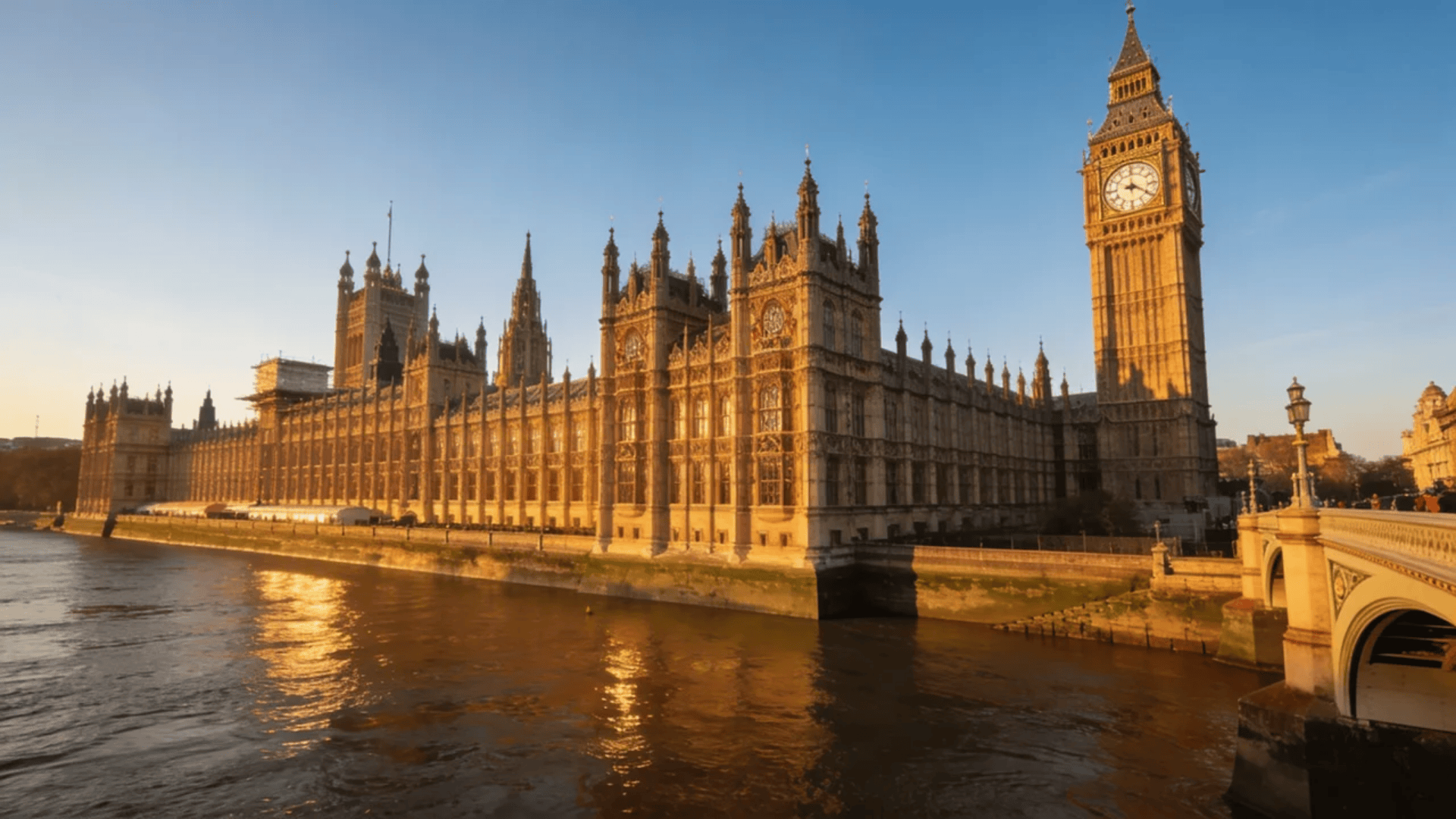 european architecture historic parliament building with clock tower beside river at sunset