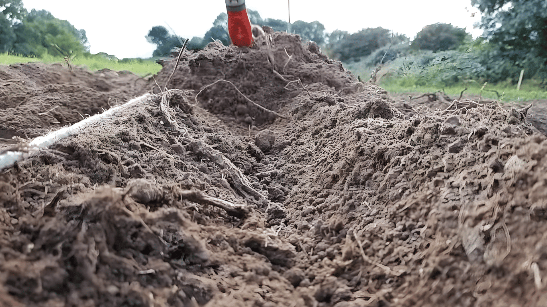 freshly dug soil trench with loose dirt and roots in a farm field close view