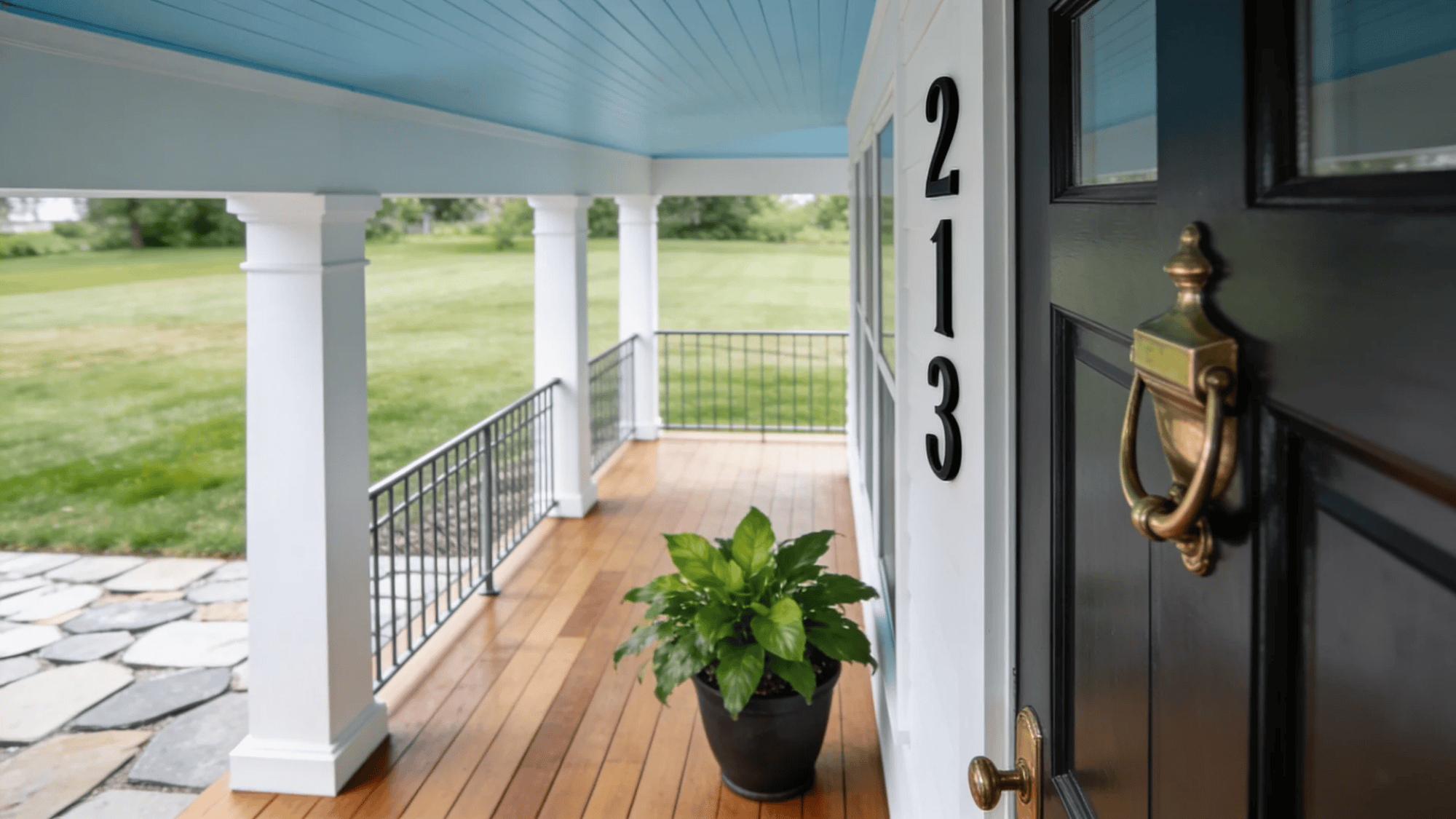 front porch with house number and potted plant near dark door overlooking green yard
