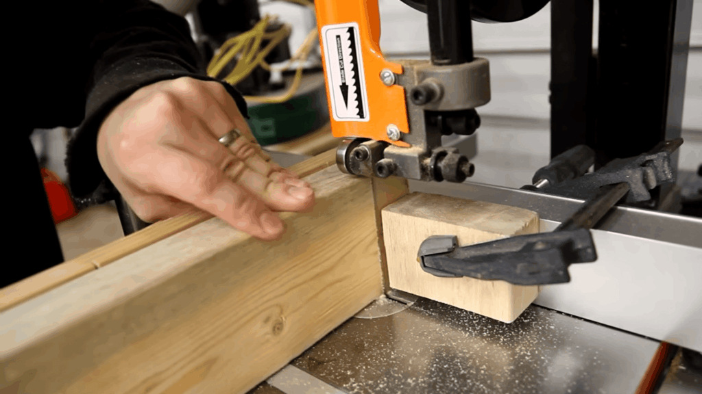 hand guiding wood through saw cutting board pieces for diy bunk beds build in workshop with tools