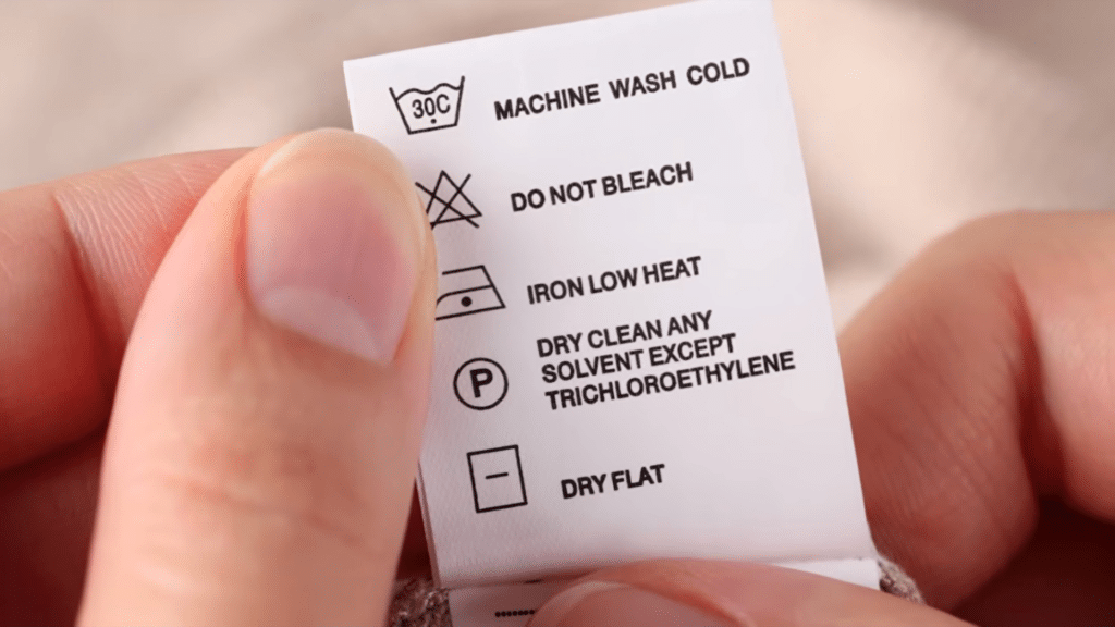 hand holding clothing care label with washing instructions