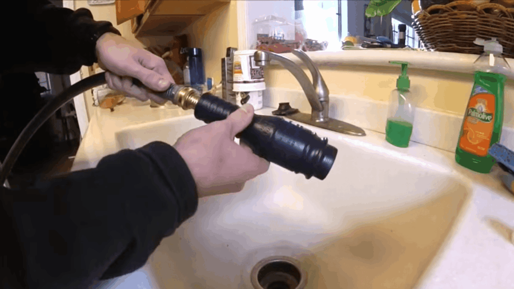 hands attaching hose tool over sink drain demonstrating how to unclog a bathtub drain using suction device