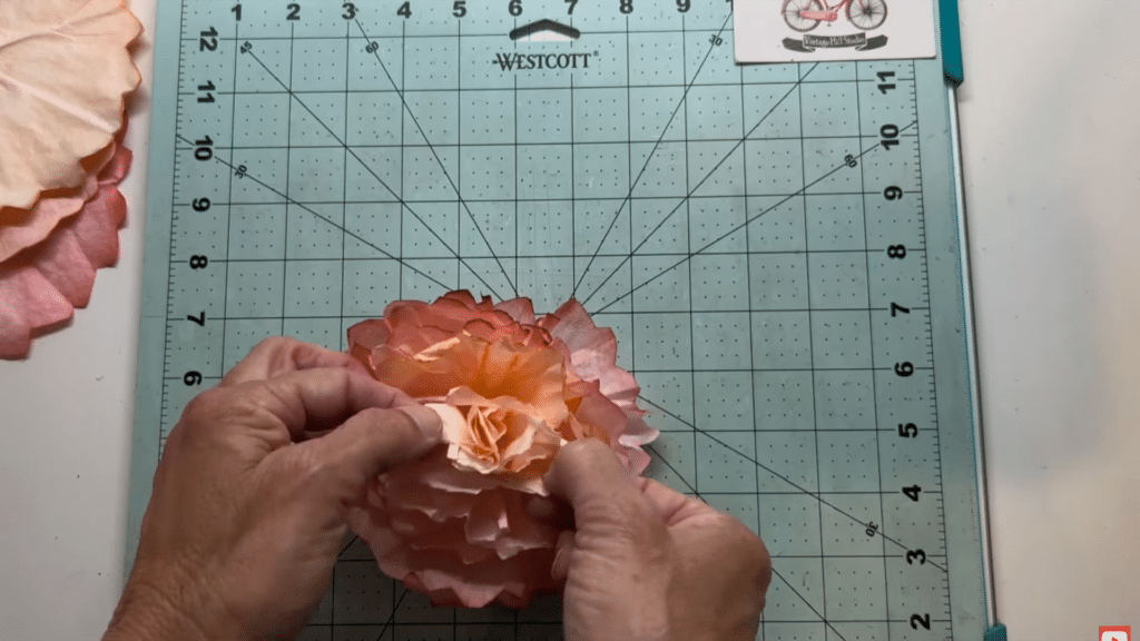 hands shaping and fluffing layered coffee filter flower petals