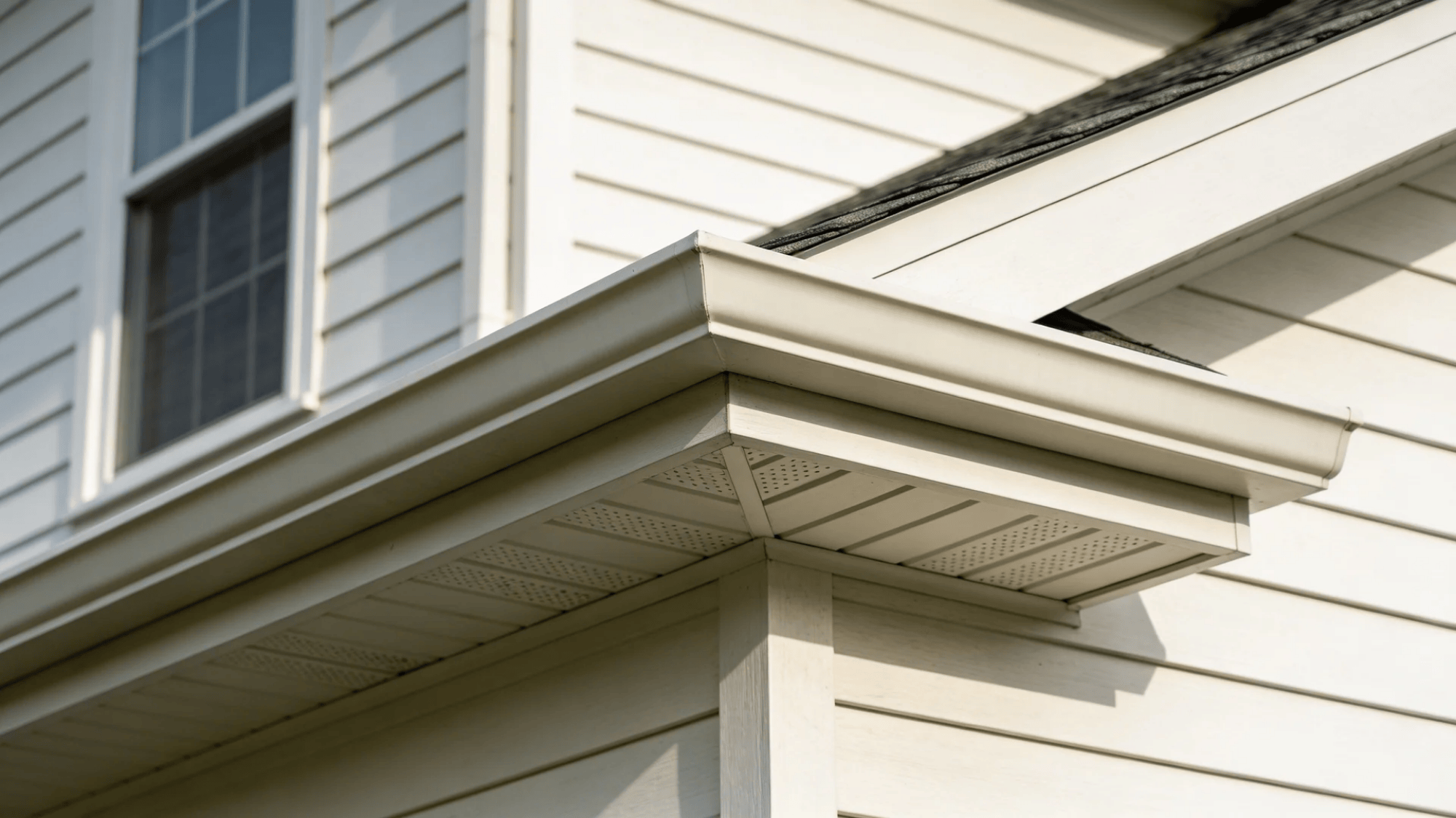 house corner with white siding roof edge and soffit under bright daylight sky
