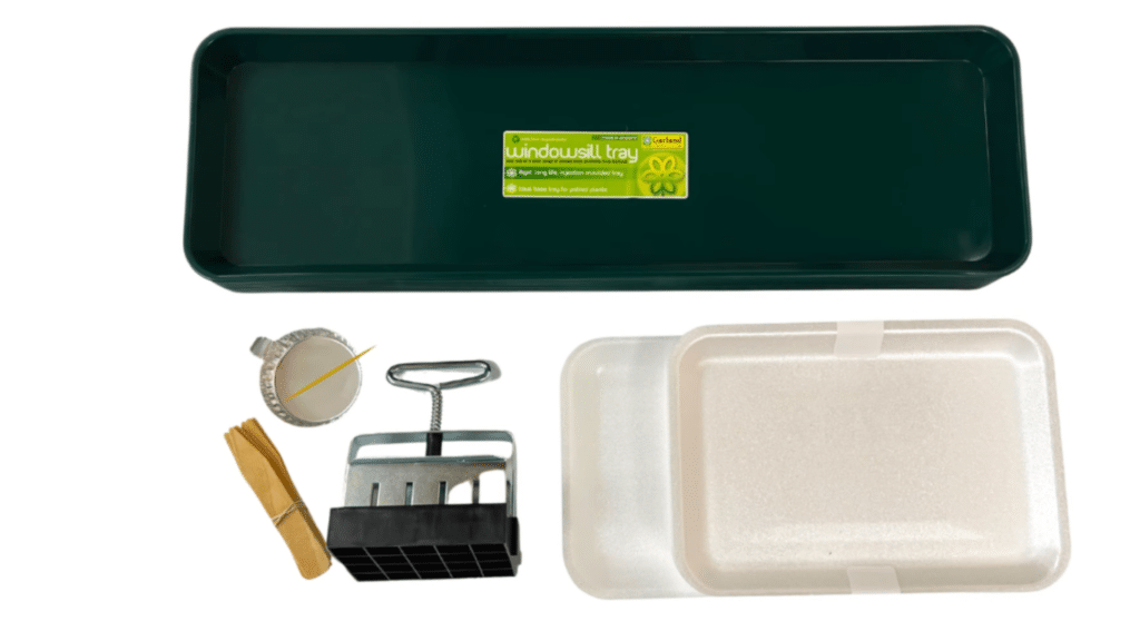 indoor gardening materials arranged including tray seed starter tool sticks and containers ready for flower growing setup