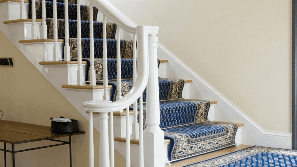 indoor staircase with white railing wooden steps and blue patterned carpet runner in a clean home interior