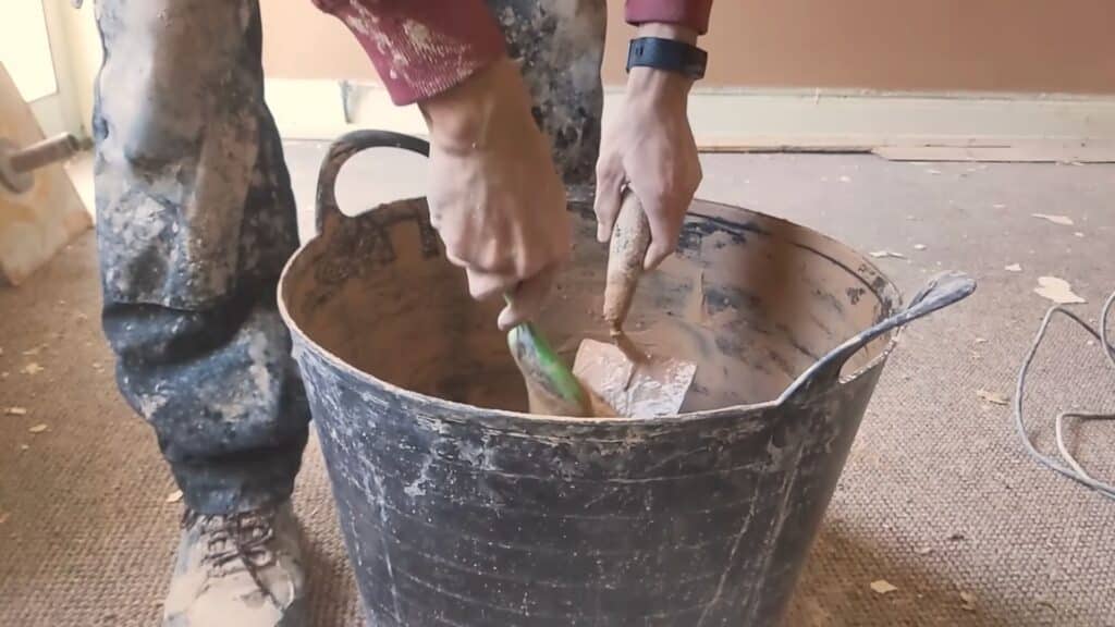 leveling plaster surface with trowel using steady pressure to remove ridges and create flat wall