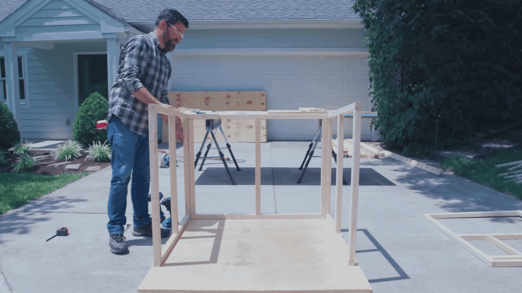 man assembling wooden frame structure on base outdoors