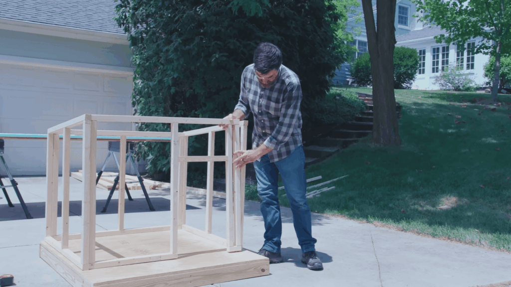 man attaching wall frame pieces to dog house structure