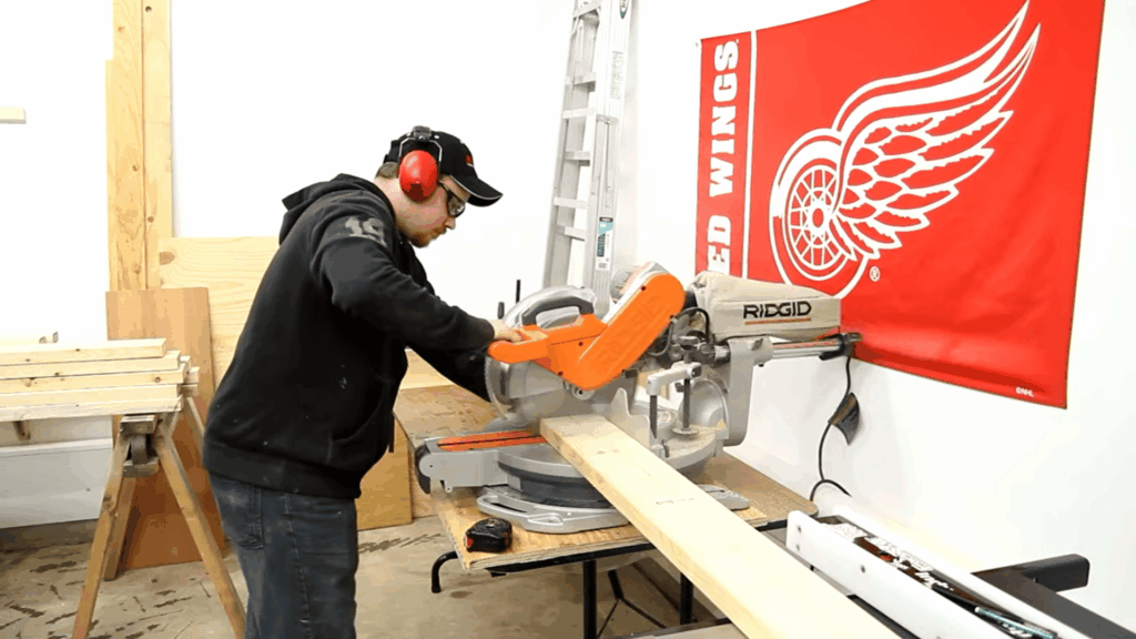 man using miter saw cutting wooden boards in workshop for diy bunk beds project with tools
