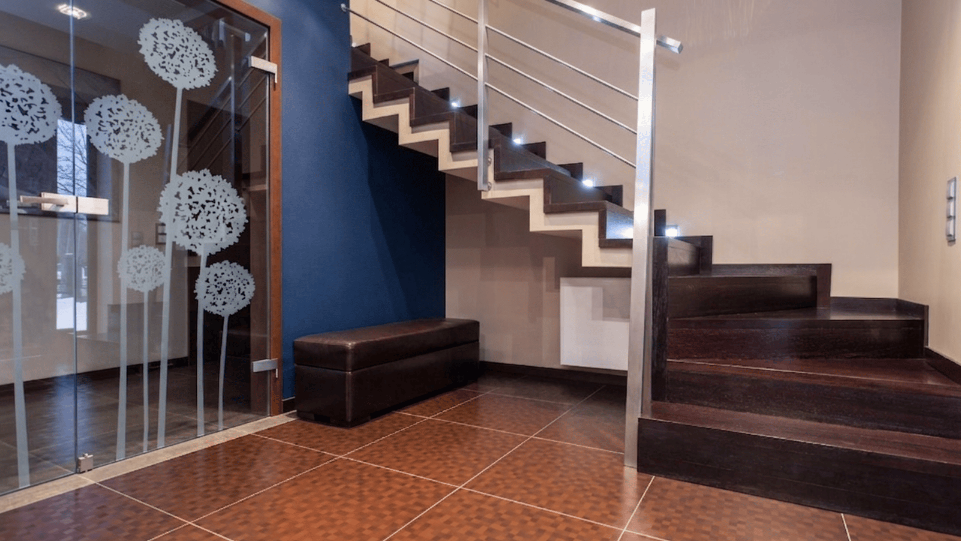 modern wooden staircase with metal railing and glass partition in a clean indoor home setting with tiled floor