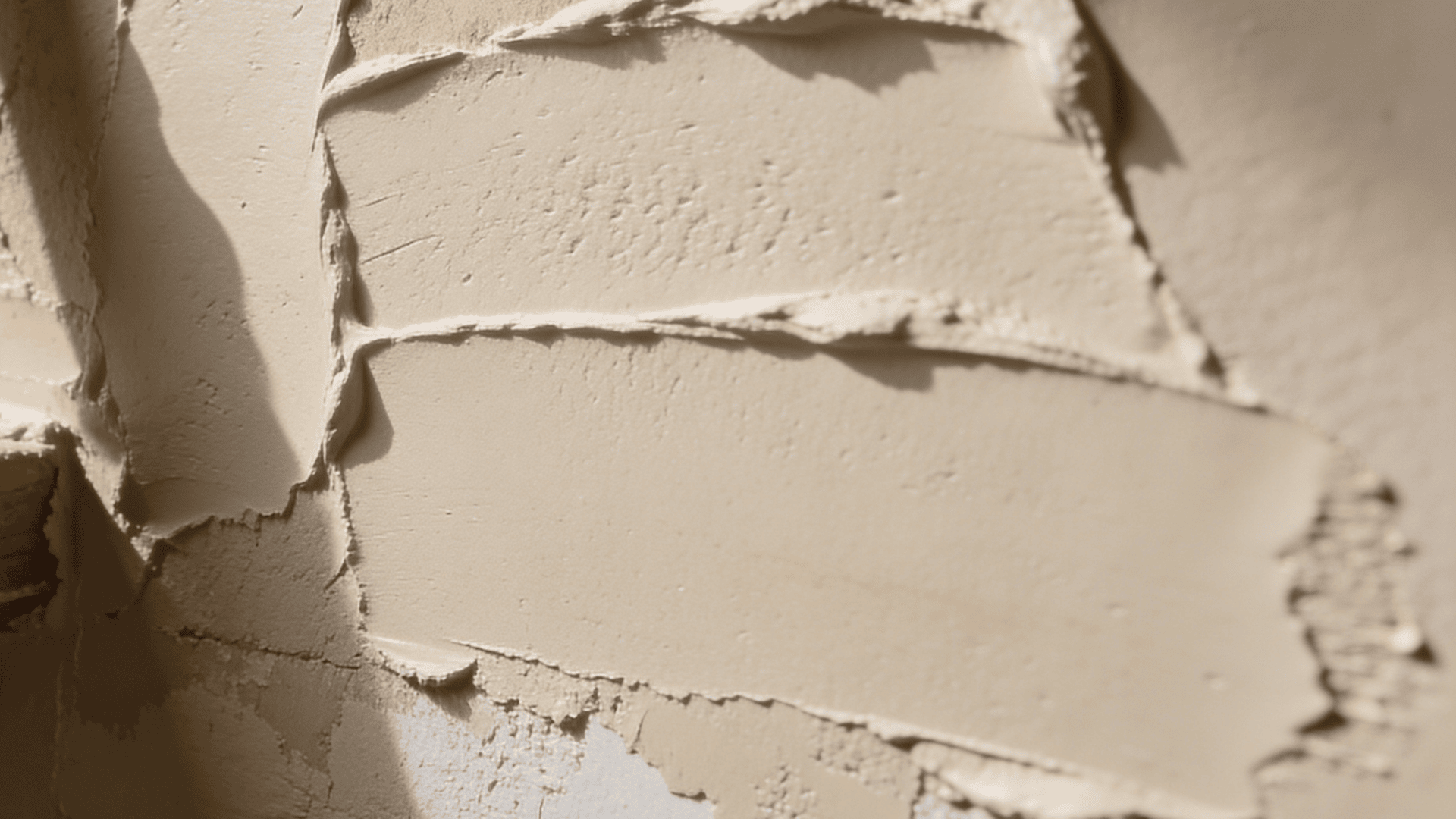 paint roller and brush resting against textured wall with raised starburst patterns under ceiling light in room