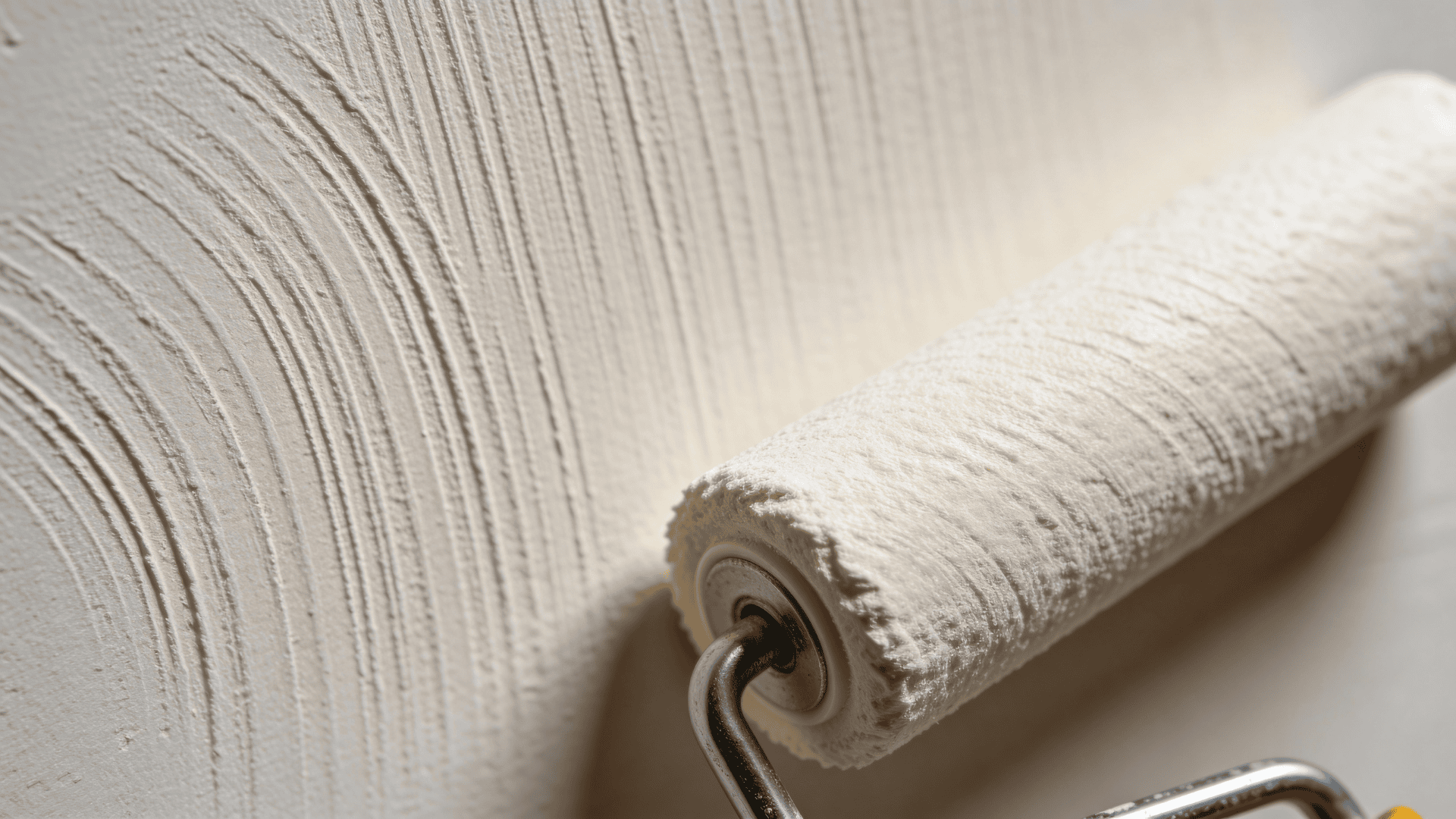 paint roller applying thick white paint over textured wall surface creating vertical ridges and even coating