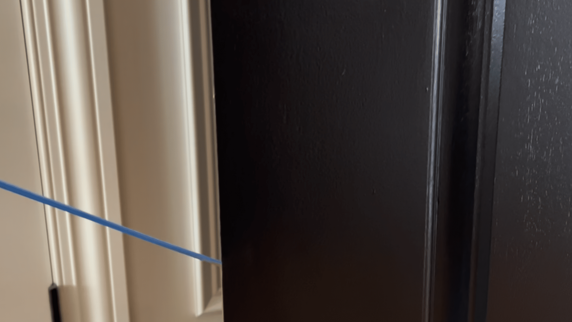 painting front door black showing final coat of black paint on door with smooth finish and taped edges