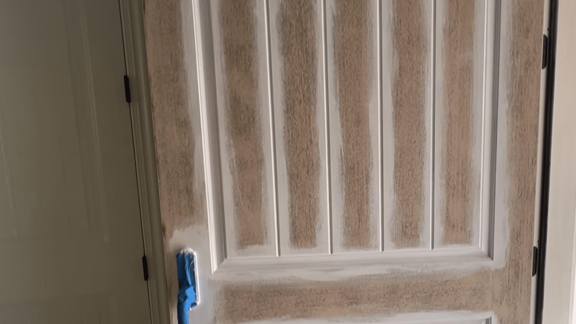 painting front door black showing freshly primed door ready for black paint with taped edges