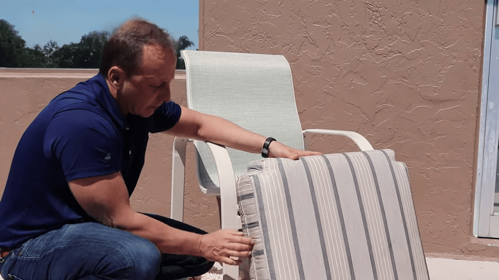 person holding and inspecting cleaned outdoor cushion after washing demonstrating how to clean sunbrella cushions for best result