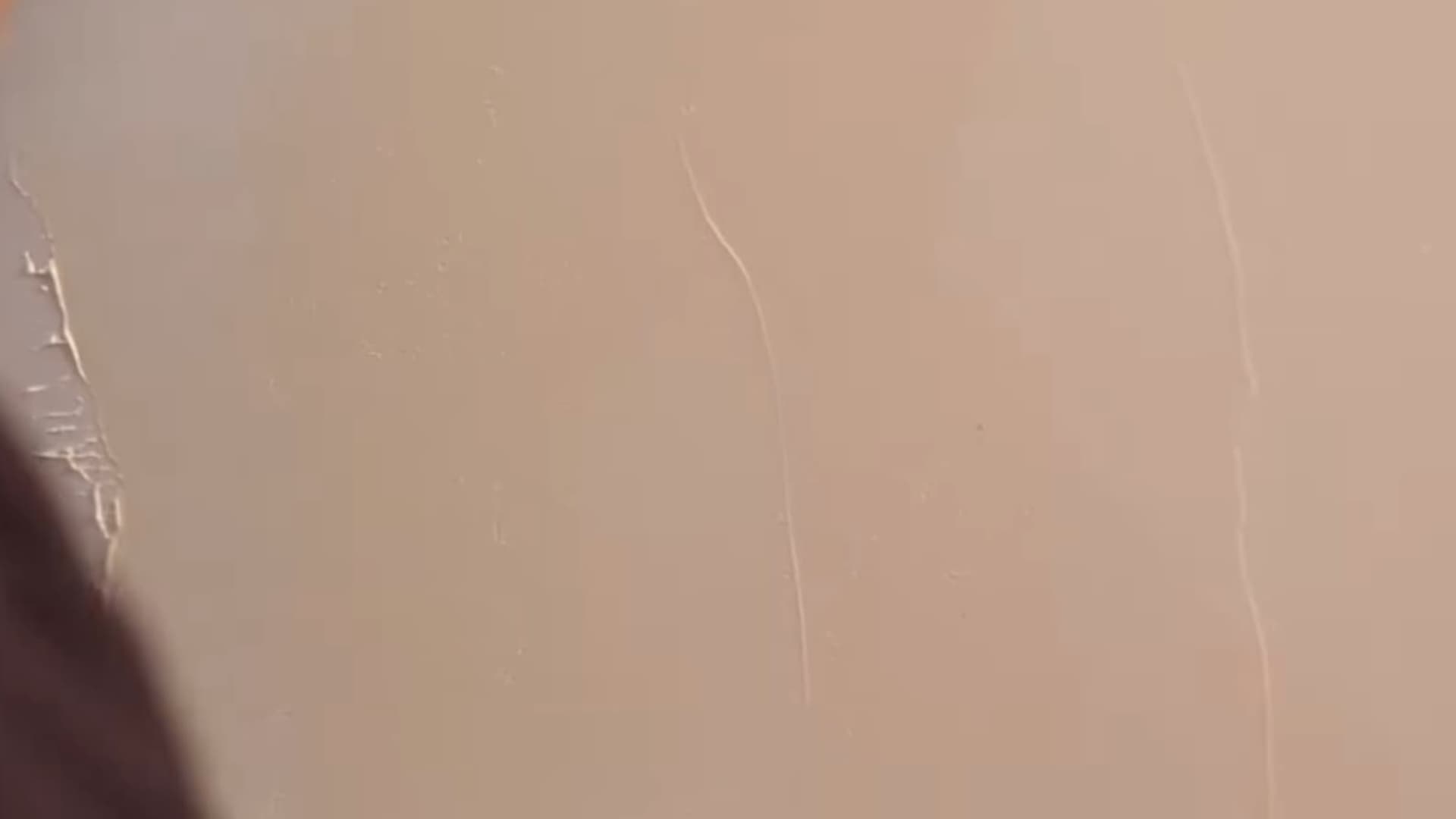 person inspecting freshly applied textured wall surface showing subtle plaster lines during interior wall finishing process