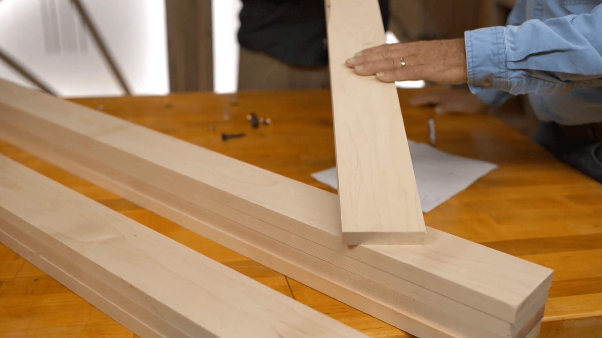 person selecting maple wood boards for diy clothes rack build on work table for strong frame design