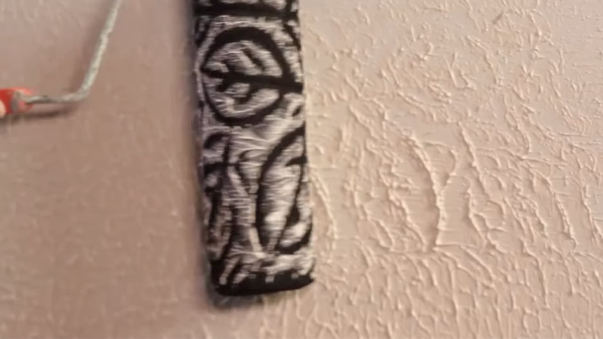 person using patterned paint roller to create decorative textured wall finish during interior wall painting process