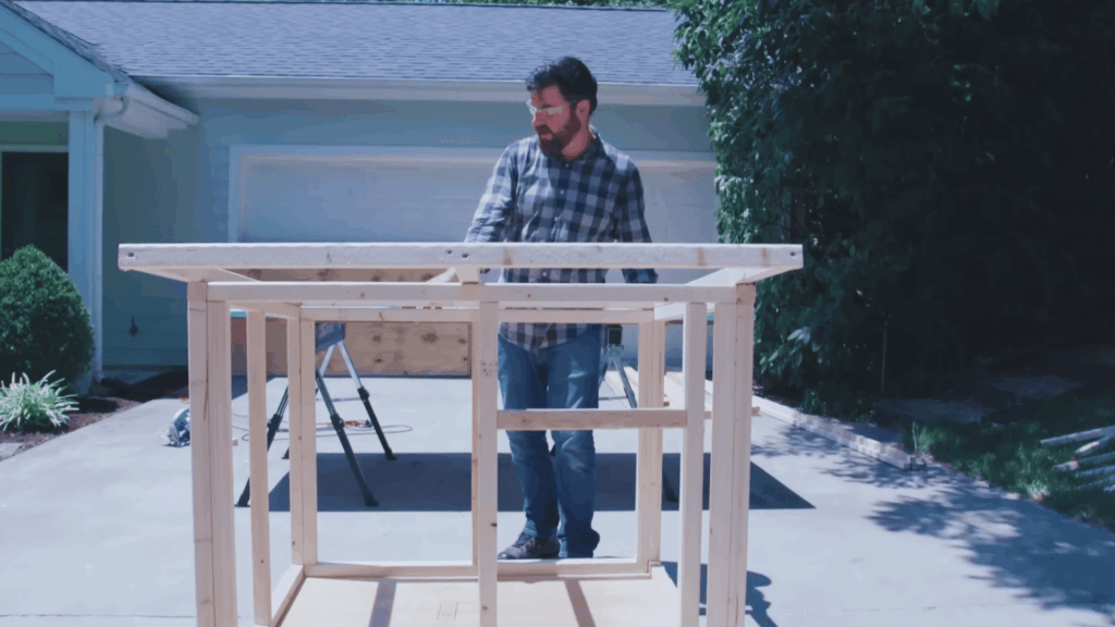 placing roof frame on top of wooden dog house frame