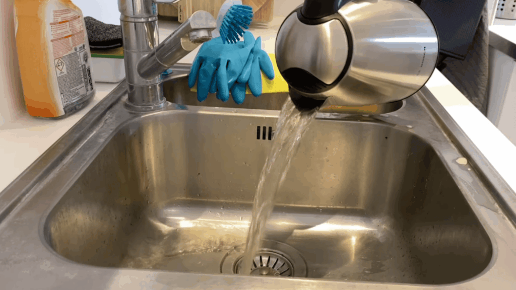 rinsing electric kettle with clean water in sink to remove vinegar and residue after cleaning process
