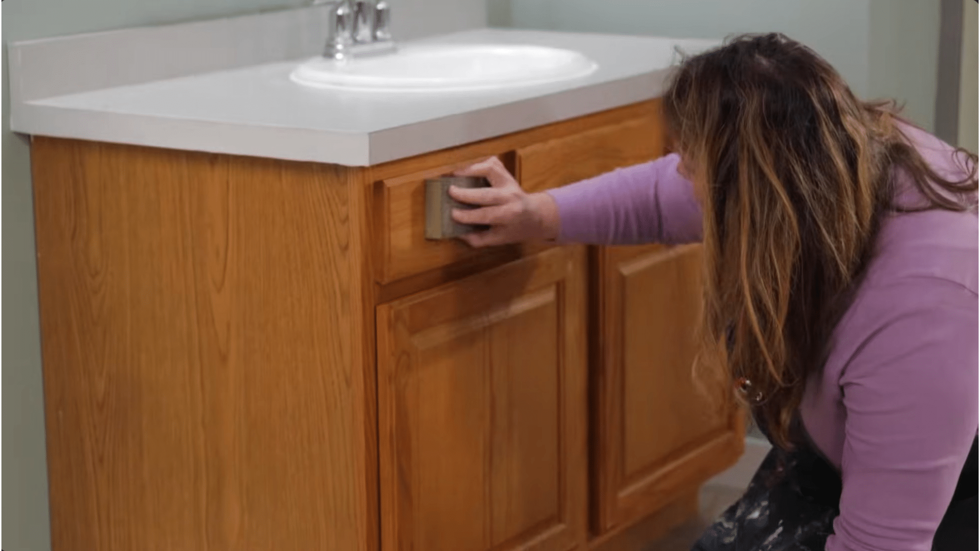 sanding surface before painting bathroom cabinets using sanding block to remove gloss and improve paint adhesion