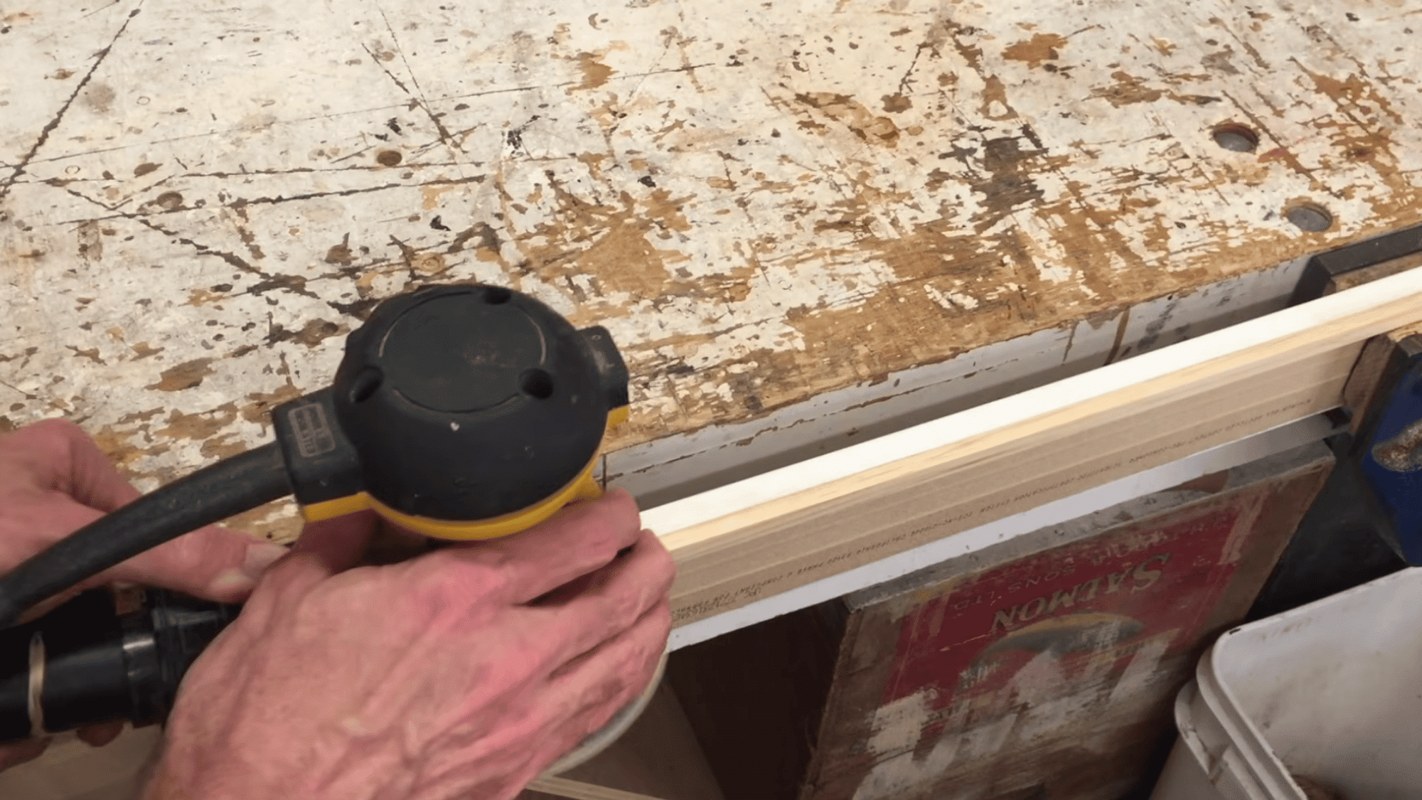 sanding wood trim edge with power sander to smooth surface before painting for mirror frame project