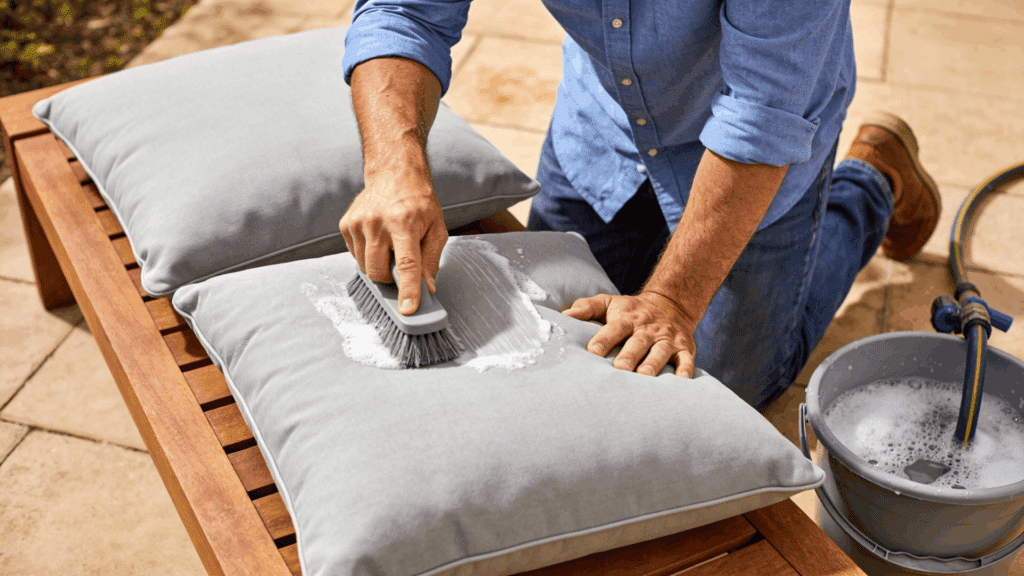 scrubbing outdoor cushion with brush and cleaner showing how to clean sunbrella cushions effectively at home