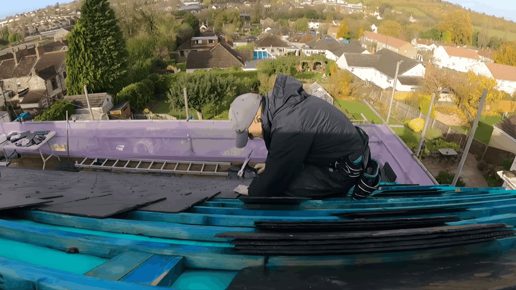 slate roof installation in action with a worker cutting tiles for a precise fit on a sloped roof structure