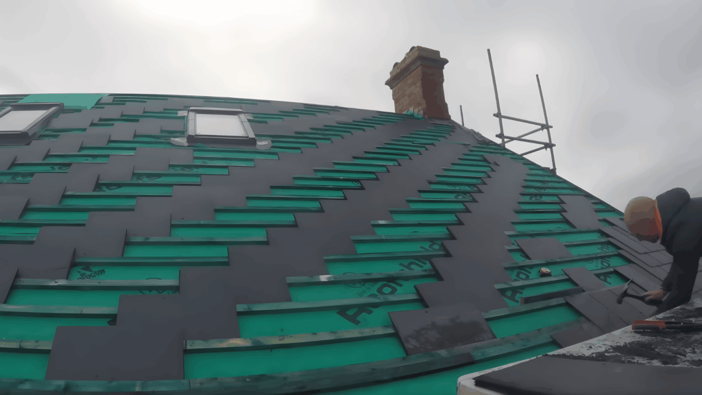 slate roof installation underway with tiles being fixed on a pitched roof using precision and tools