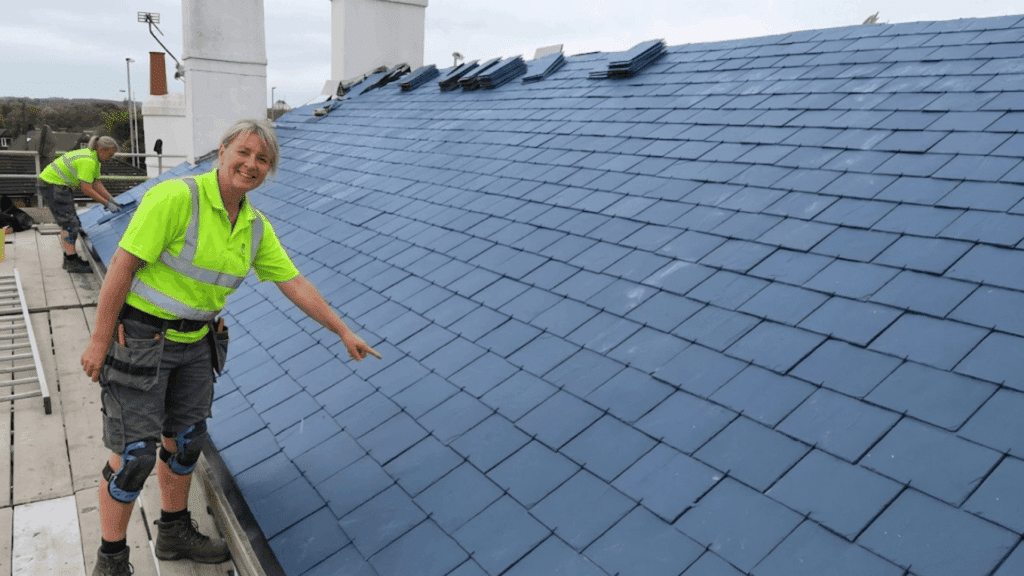 slate roof installation with a worker checking the alignment of tiles to ensure a secure and uniform finish